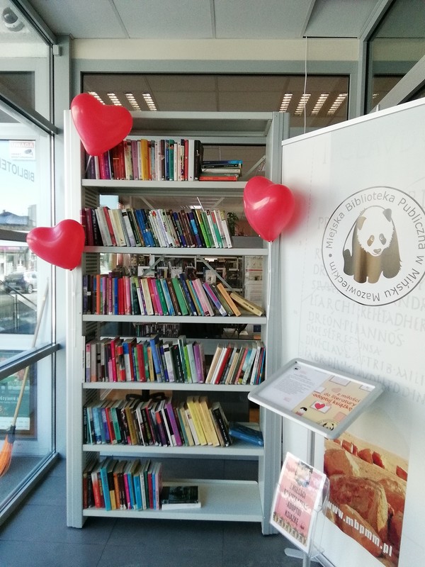 Zdjęcie przedstawiające ozdobioną balonowymi sercami półkę z książkami, które można adoptować 