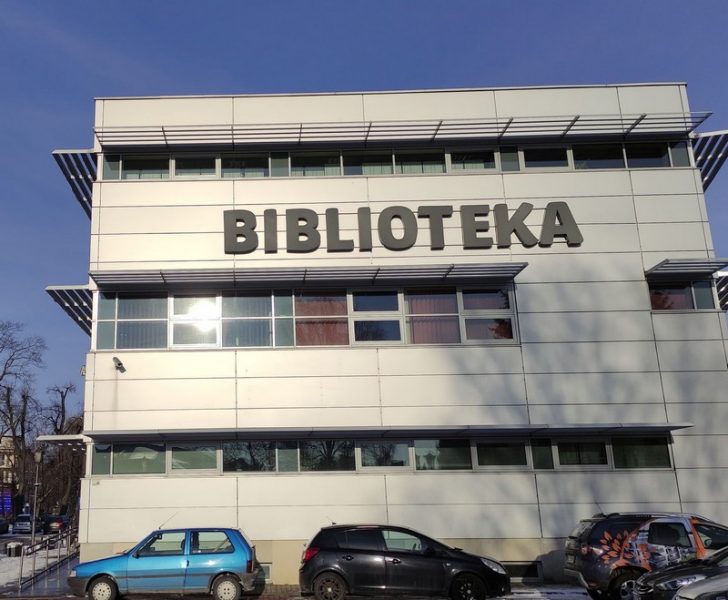 Zdjęcie przedstawia budynek biblioteki od strony parkingu z dużym napisem biblioteka