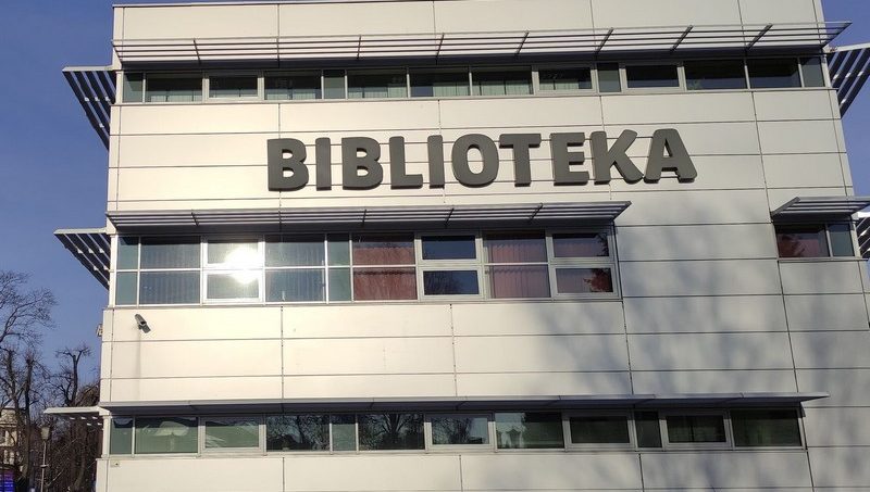 Zdjęcie przedstawia budynek biblioteki od strony parkingu z dużym napisem biblioteka