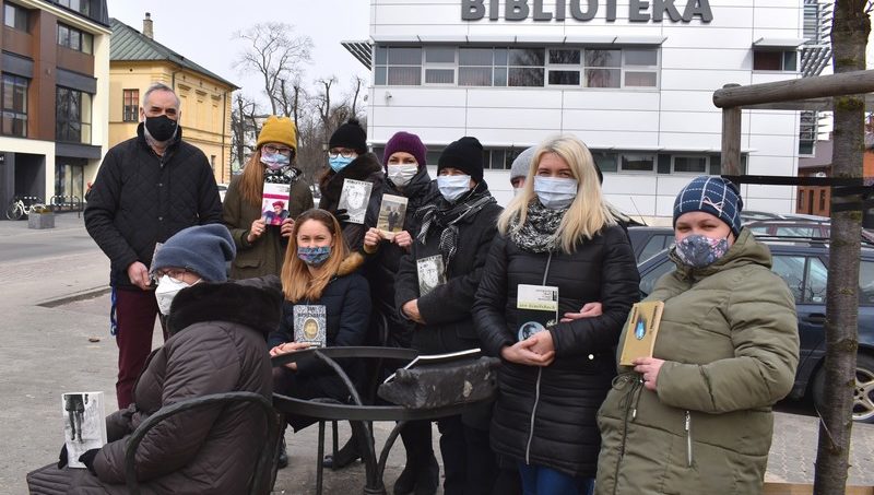 Bibliotekarze przy zniszczonej ławeczce Jana Himilsbacha w Mińsku Mazowieckim trzymają książki napisane przez Himilsbacha w rękach